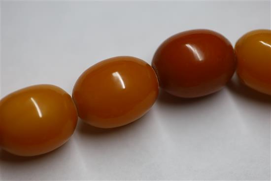 A single strand graduated oval amber bead necklace, gross weight 104 grams, 86cm.